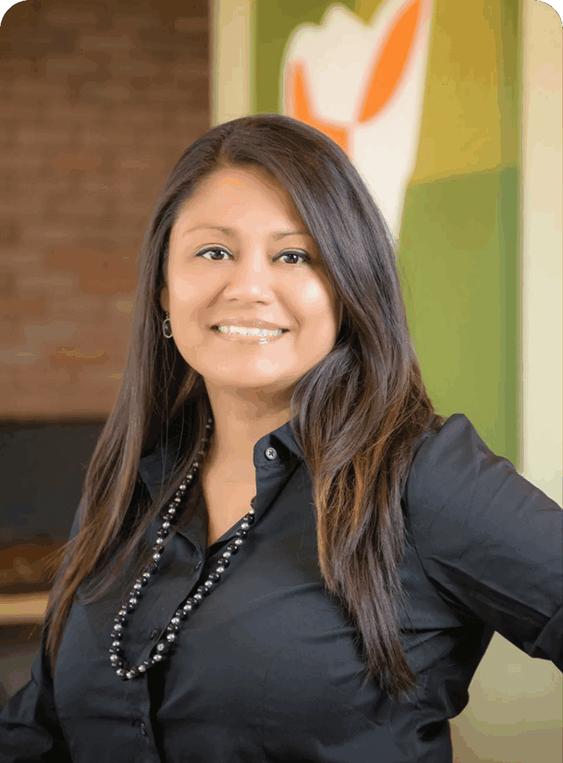 Confident woman smiling warmly, dressed in black with a beaded necklace.