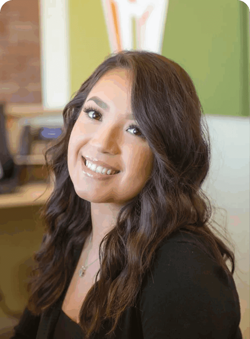 Smiling woman with long wavy hair in a cozy indoor setting.
