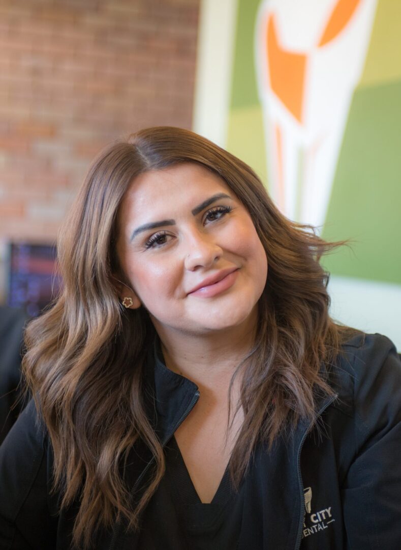 A smiling woman with wavy brown hair and a black top.