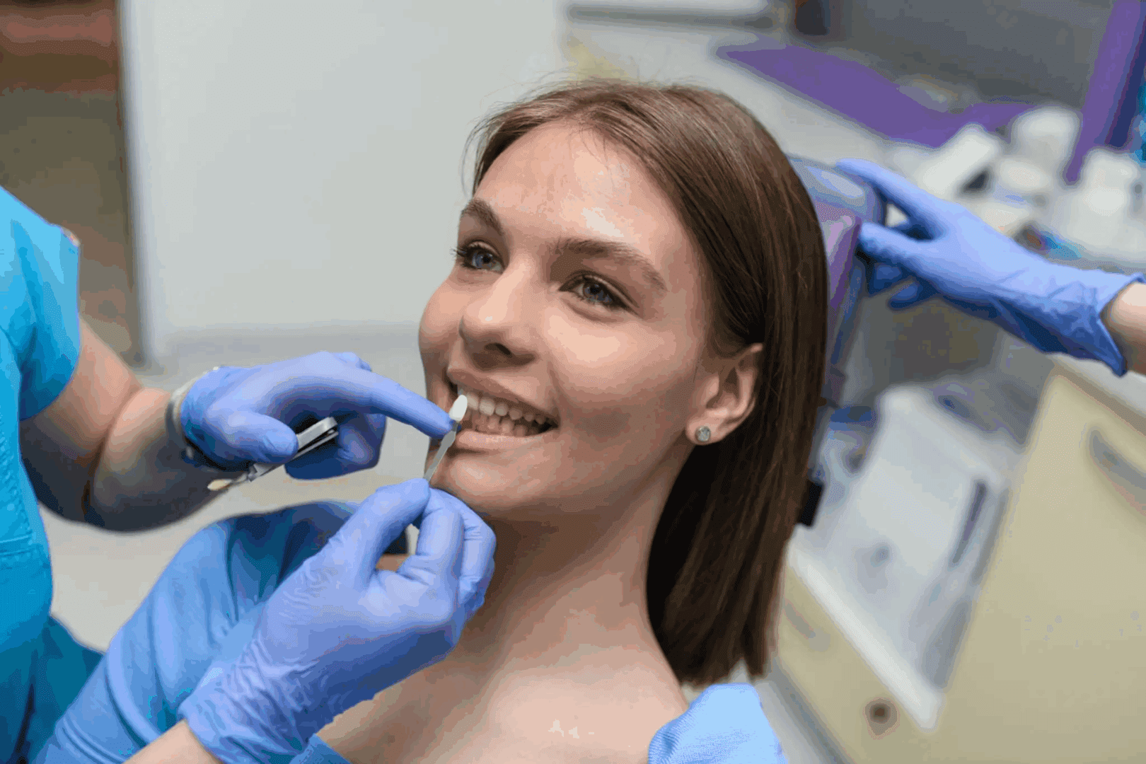 A woman receiving dental care from a dentist wearing blue gloves.